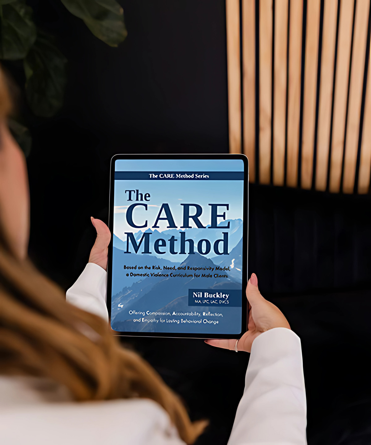 Client reading The CARE Method by Nil Buckley on a tablet, a core trauma-informed resource offered by Vivus Counseling for domestic violence and personal growth
