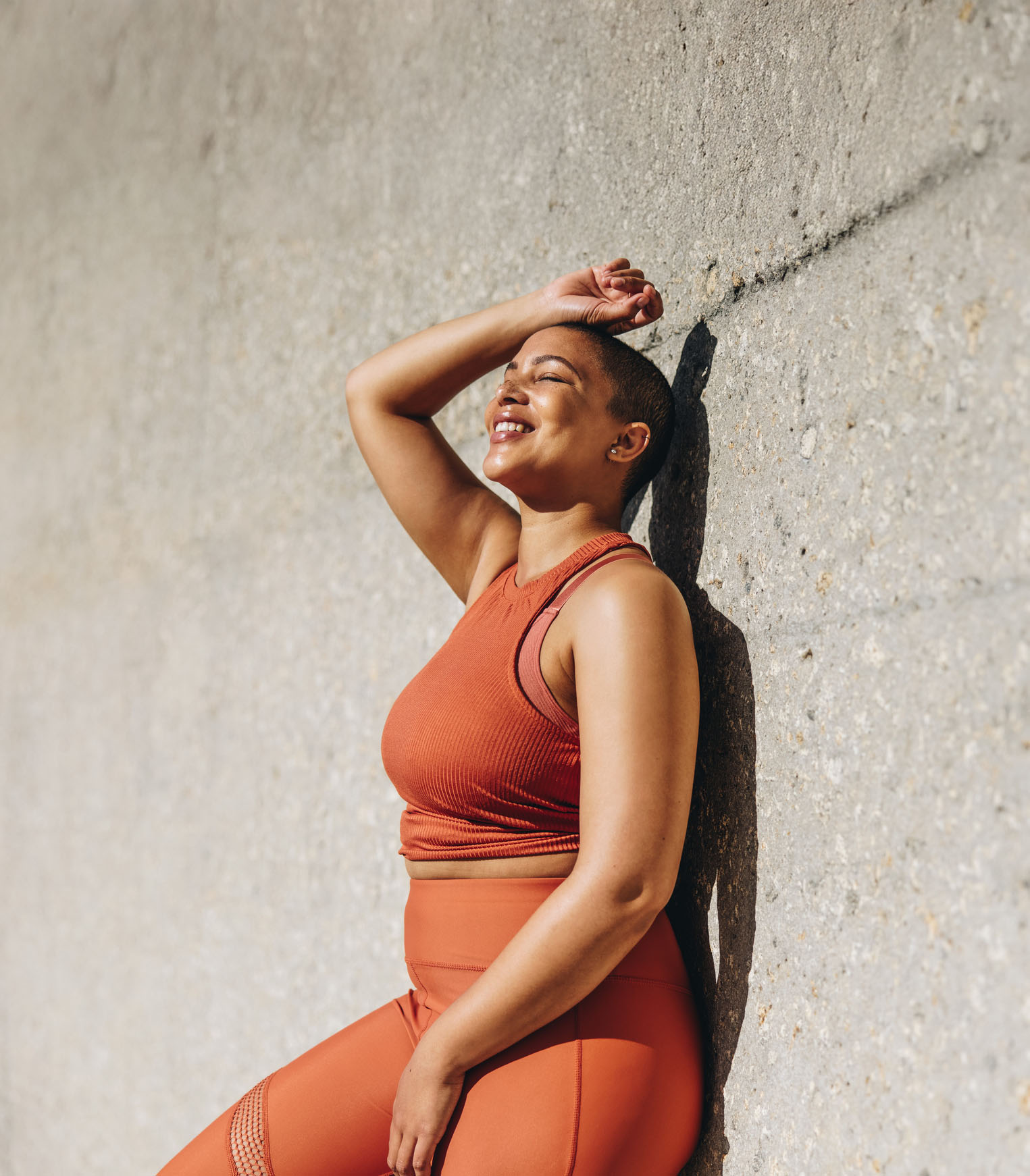 Confident woman in activewear smiling in the sun, representing empowerment, self-acceptance, and positive outcomes from mental health support