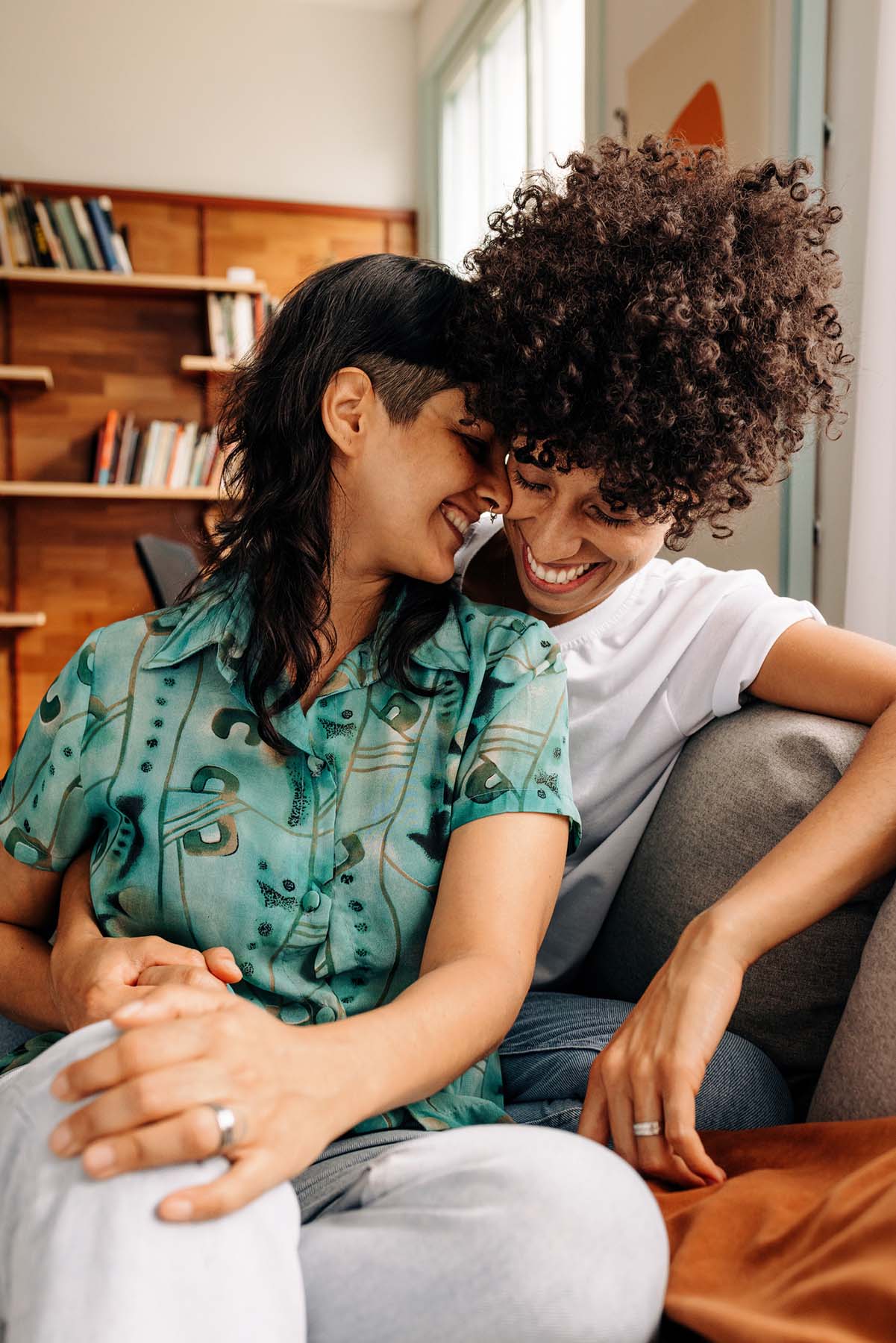 LGBTQ+ couple smiling and embracing on a couch, representing affirming and inclusive relationship therapy at Vivus Counseling in Colorado Springs