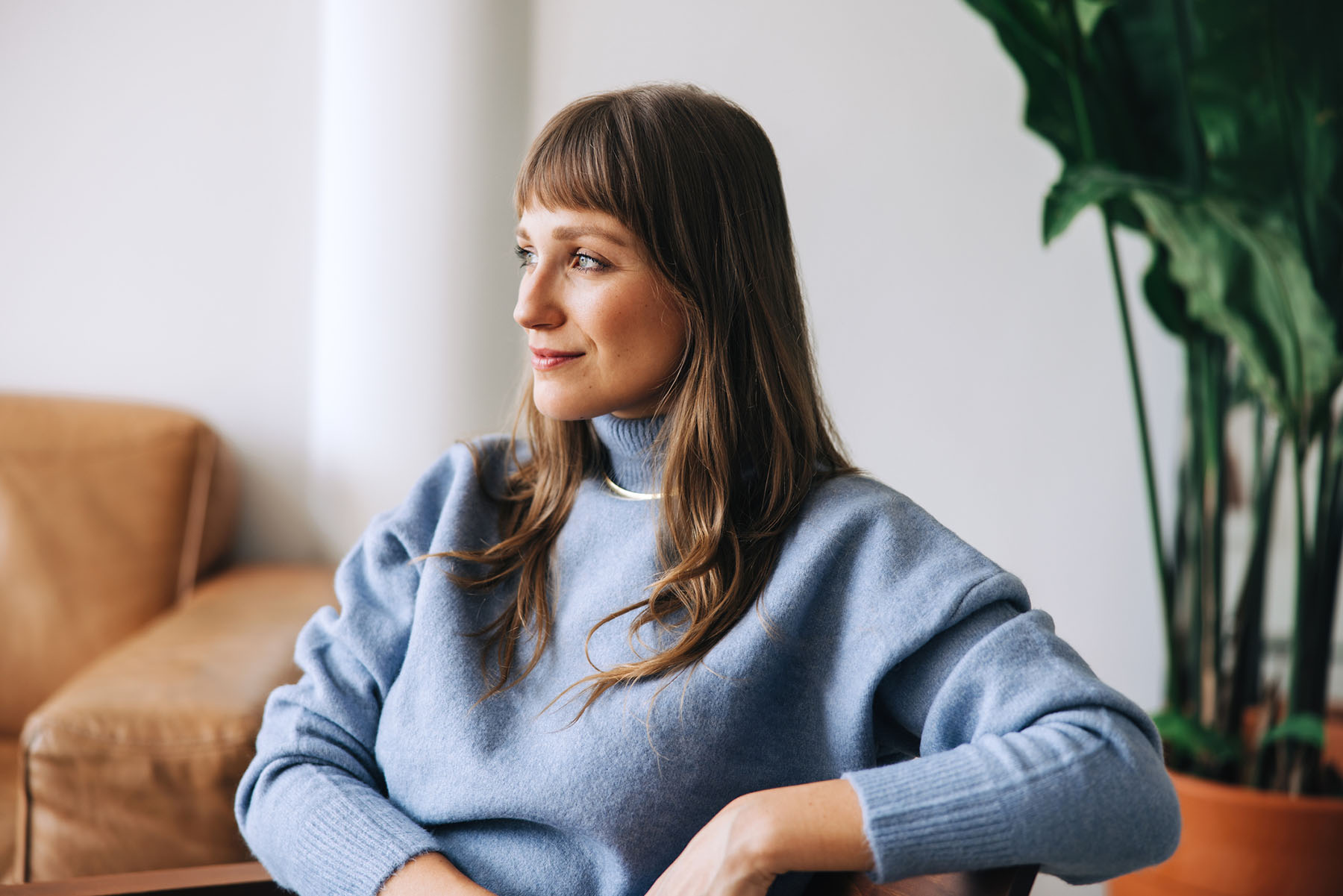 Young woman sitting calmly in a therapy office at Vivus Counseling Colorado Springs, reflecting during an individual counseling session focused on emotional wellness
