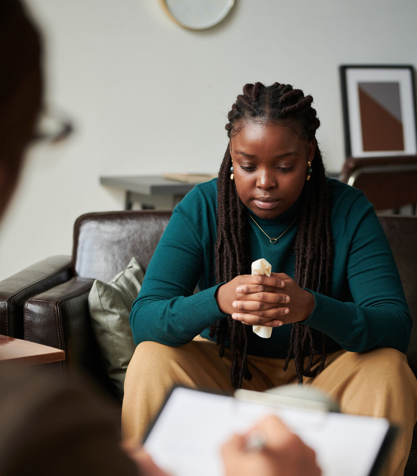 Young woman in therapy session holding tissues, depicting a vulnerable moment of seeking help for depression or trauma