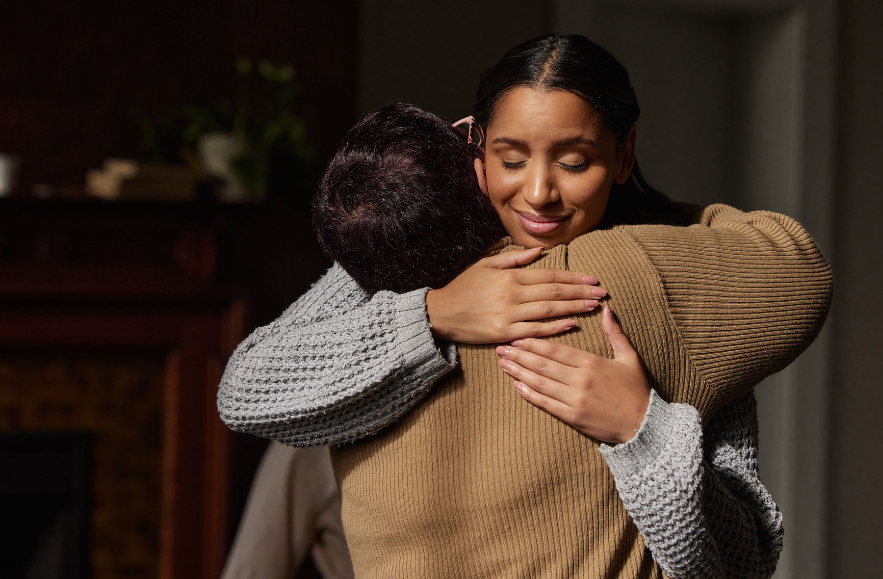Woman embracing another person in a warmly lit room, symbolizing grief counseling and emotional support services