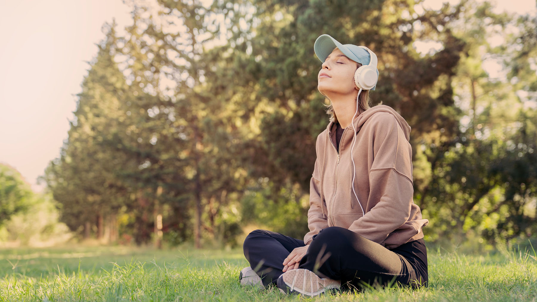 Woman meditating in nature with headphones, representing mindfulness and holistic approaches to mental health and anxiety relief