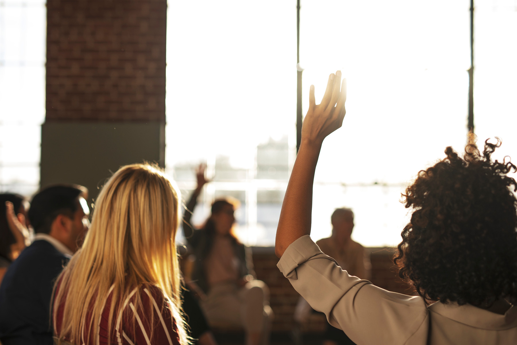 Group therapy participant raising hand in a sunlit session, symbolizing active participation and healing through group counseling in Colorado Springs
