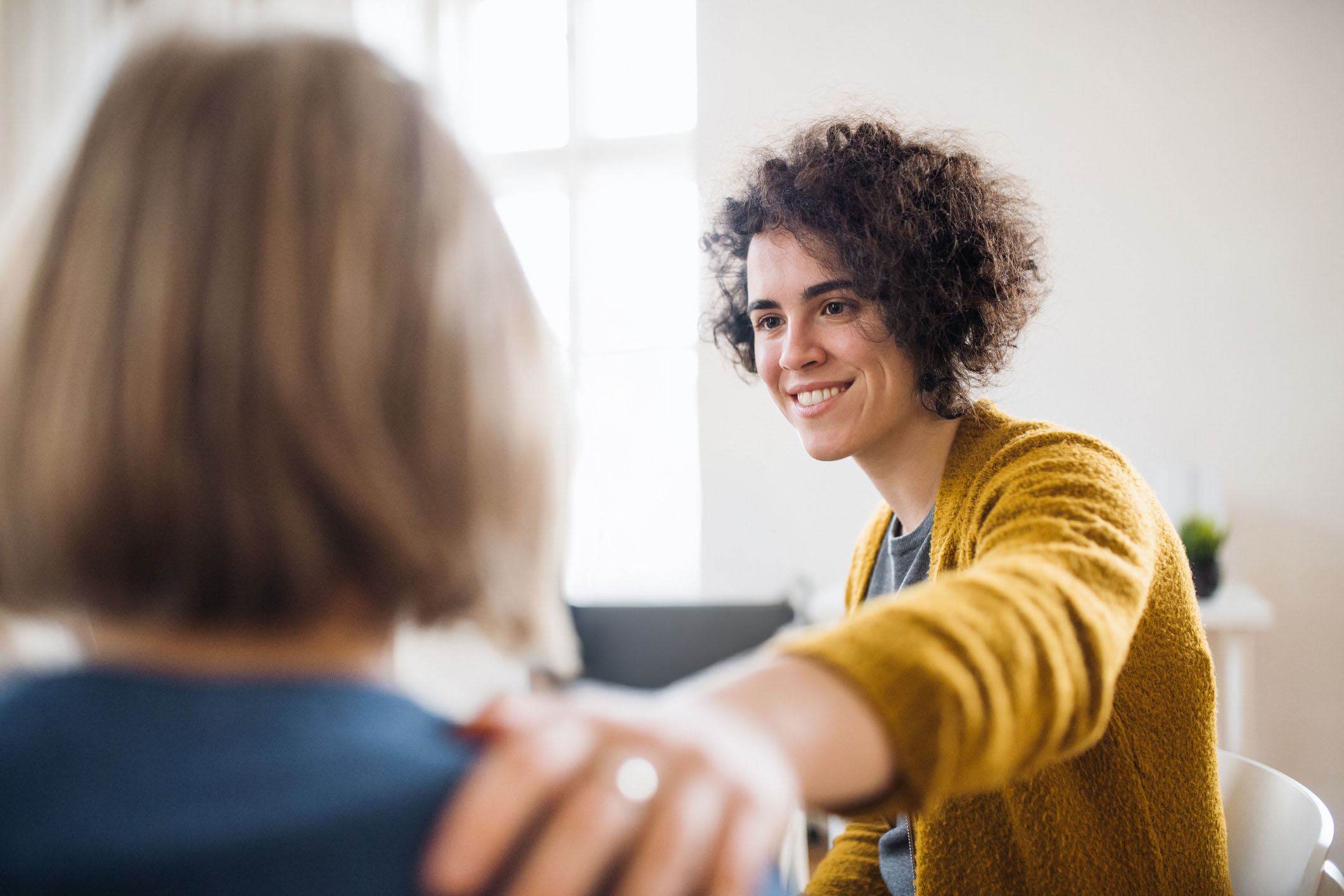 Smiling therapist comforting client with hand on shoulder, reflecting empathy and personalized mental health care at Vivus Counseling