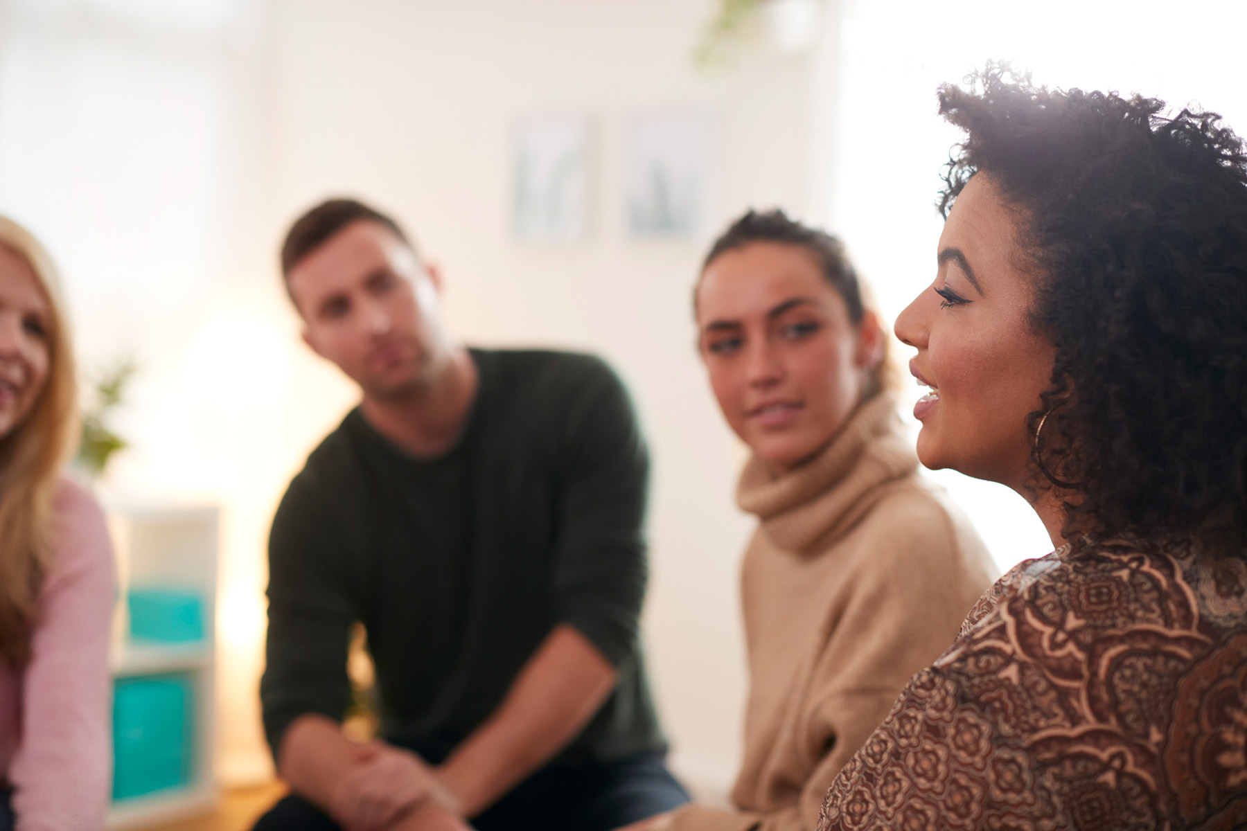 Woman speaking in group therapy session with others listening, representing open communication and healing in a safe counseling environment