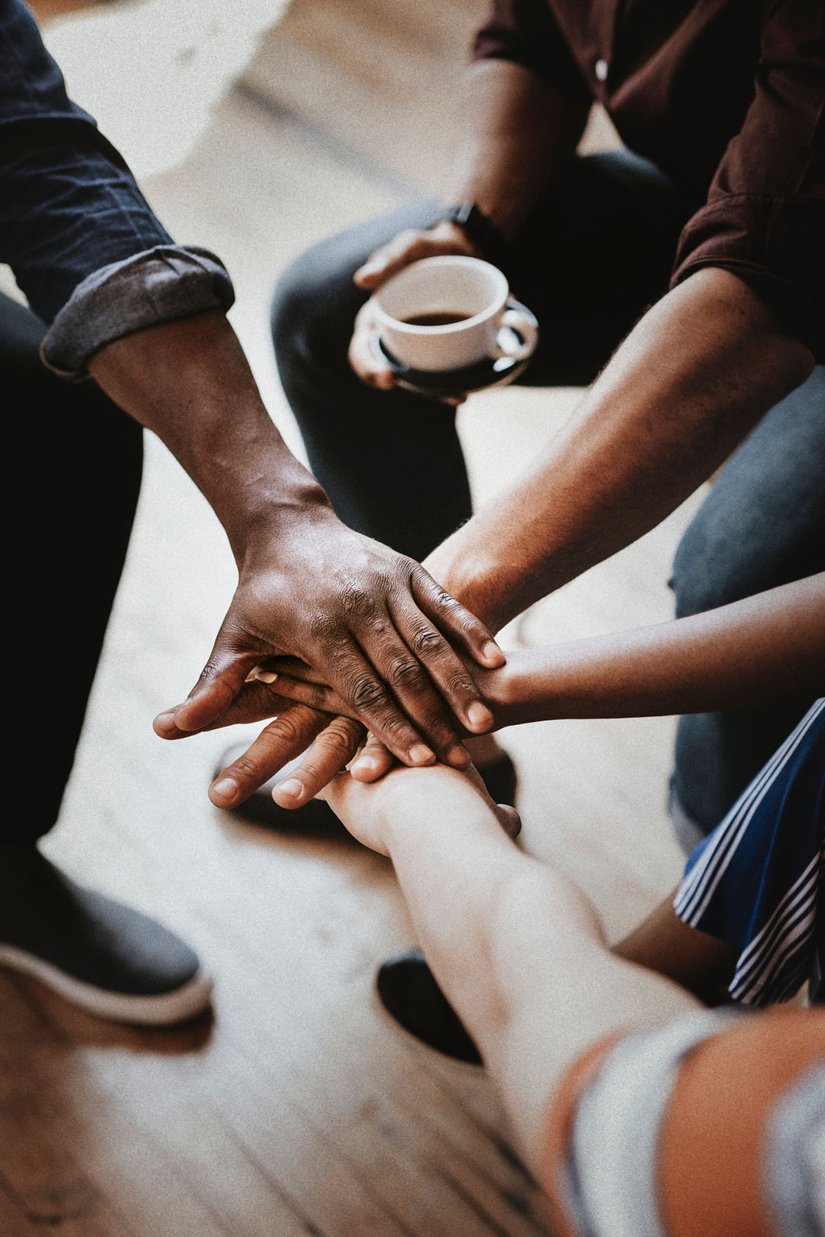 Group of diverse hands stacked together showing unity and trust, symbolizing supportive group therapy and connection through counseling